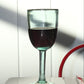 Handblown recycled wine glass on a reflective surface with a lamp in the background