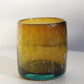 Amber bubbly glass tumbler with textured surface on a white background