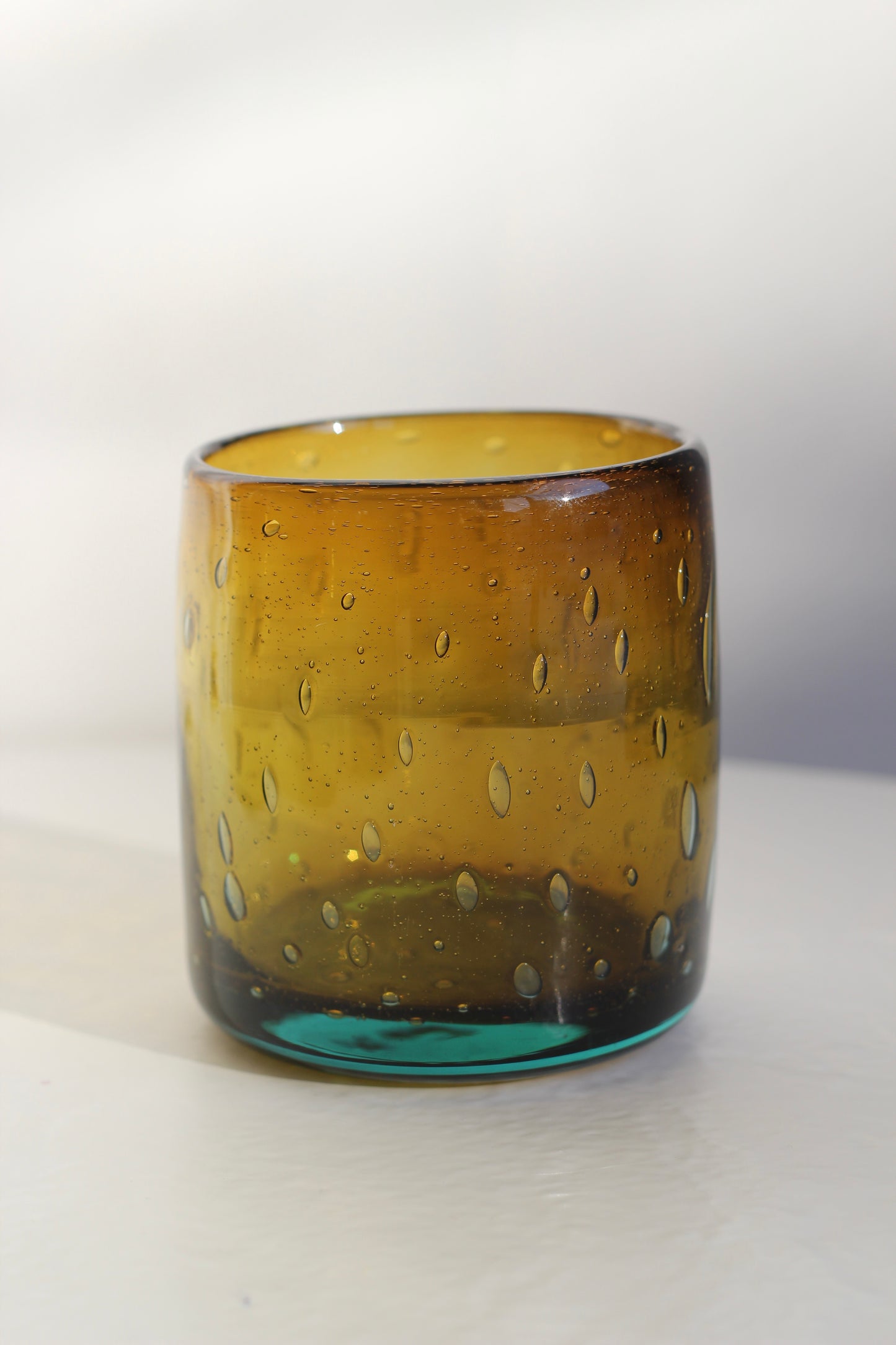 Amber bubbly glass tumbler with textured surface on a white background