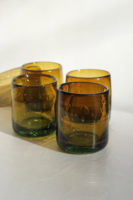 Four amber chunky handblown tumblers on a white surface