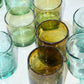 Collection of green and clear handblown glass tumblers on a white surface