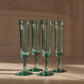 Four handblown recycled glass champagne flutes on a table