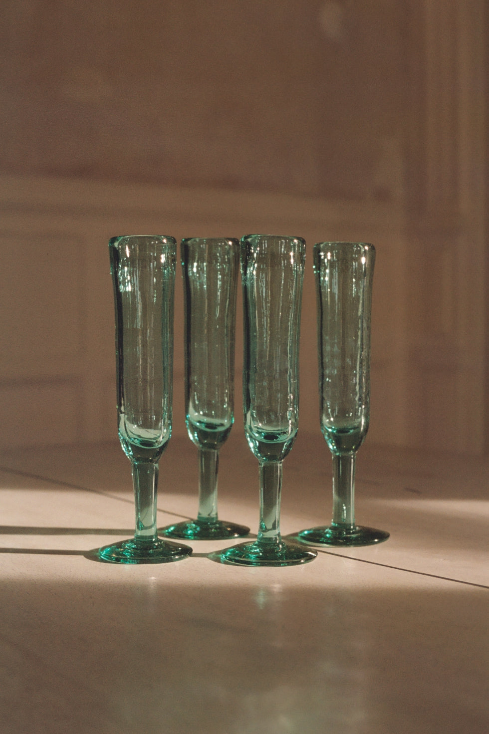Four handblown recycled glass champagne flutes on a table