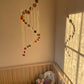A colorful handmade baby mobile with origami-style paper planets hanging over a crib in a nursery room.