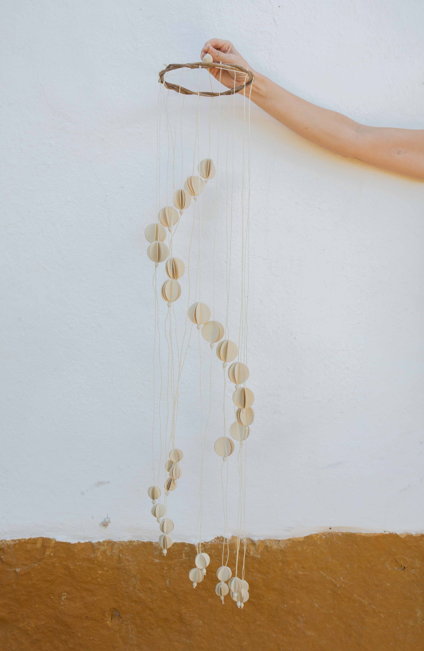 Decorative hanging crib mobile against a white wall.