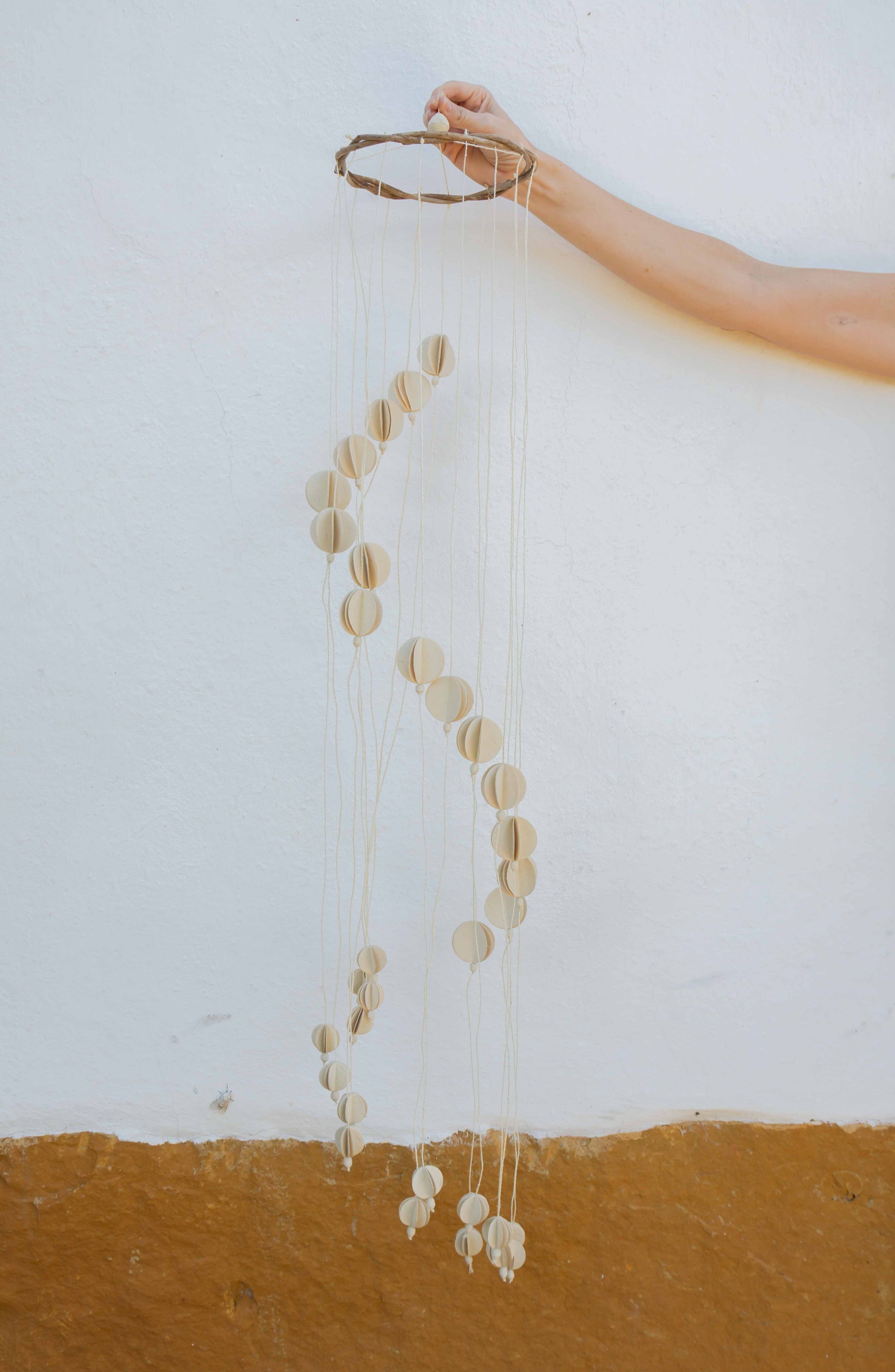 Decorative hanging crib mobile against a white wall.