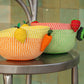 Three colorful mini woven fruit bowls on a metal stool.