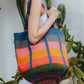 Woman holding a colorful striped oversized tote bag with a cactus background