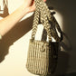Hand holding a striped handwoven bag against a neutral background