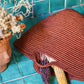 Handwoven copper basket bag on turquoise tiles