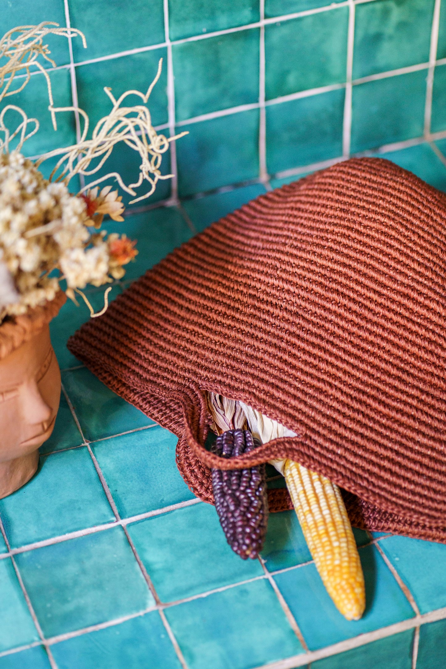 Handwoven copper basket bag on turquoise tiles