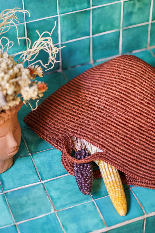 Handwoven copper basket bag on turquoise tiles