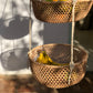 Two-tier hanging handwoven baskets made of natural fibers displayed outdoors with fruits inside, likely handcrafted from materials sourced from the Amazon rainforest.
