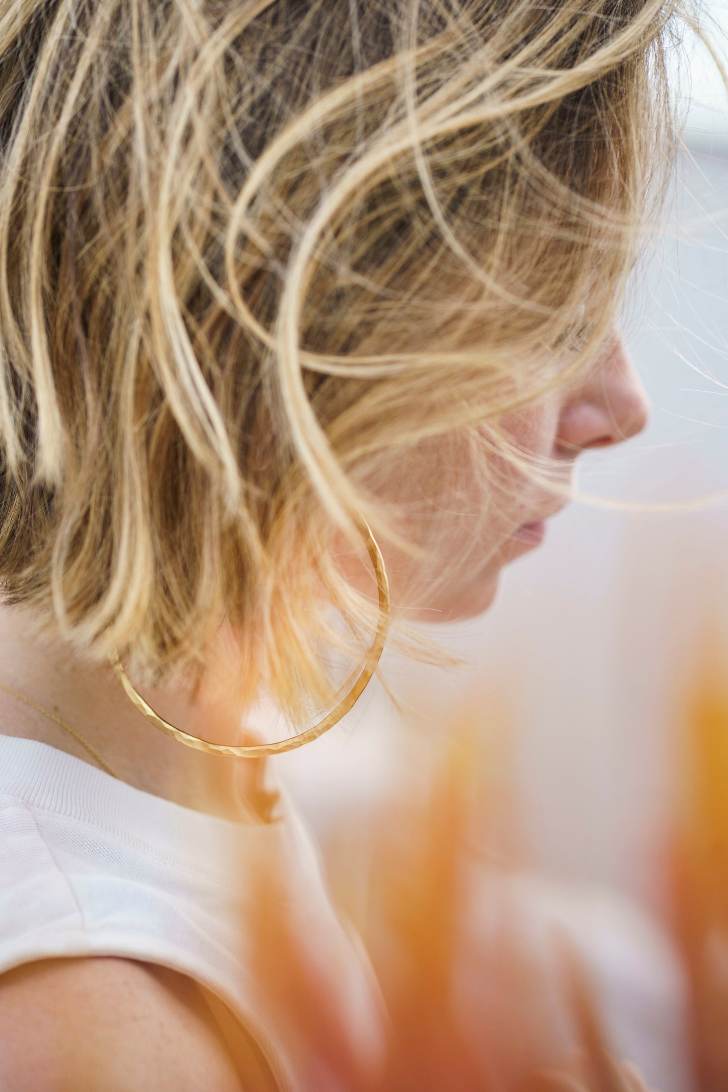 Large hammered gold hoop earrings on a woman