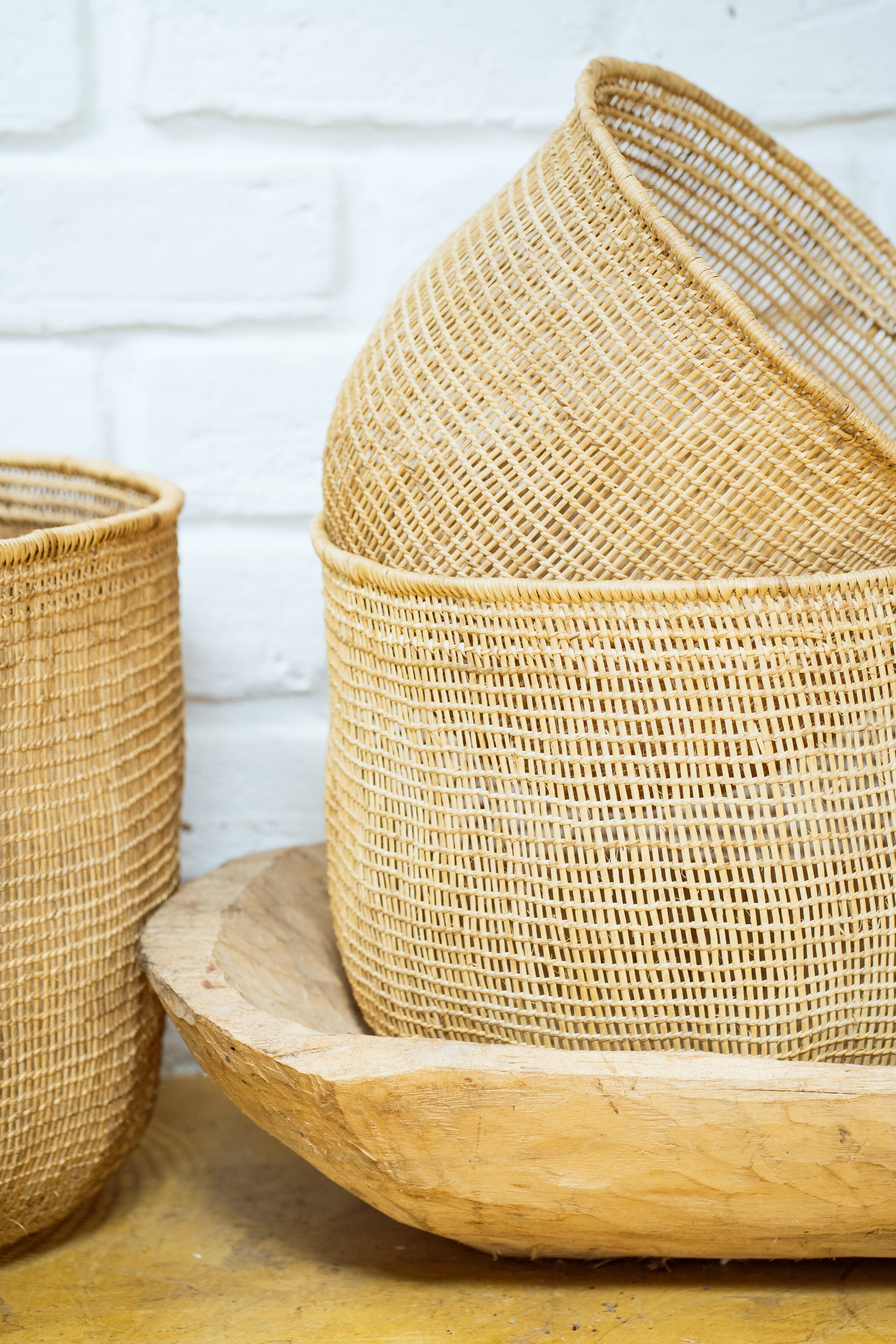 A set of natural, handwoven baskets of varying sizes made from a natural vine fiber, displayed stacked together.